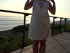 Dojrzała kobieta w białej sukience uprawia seks na balkonie na zewnątrz